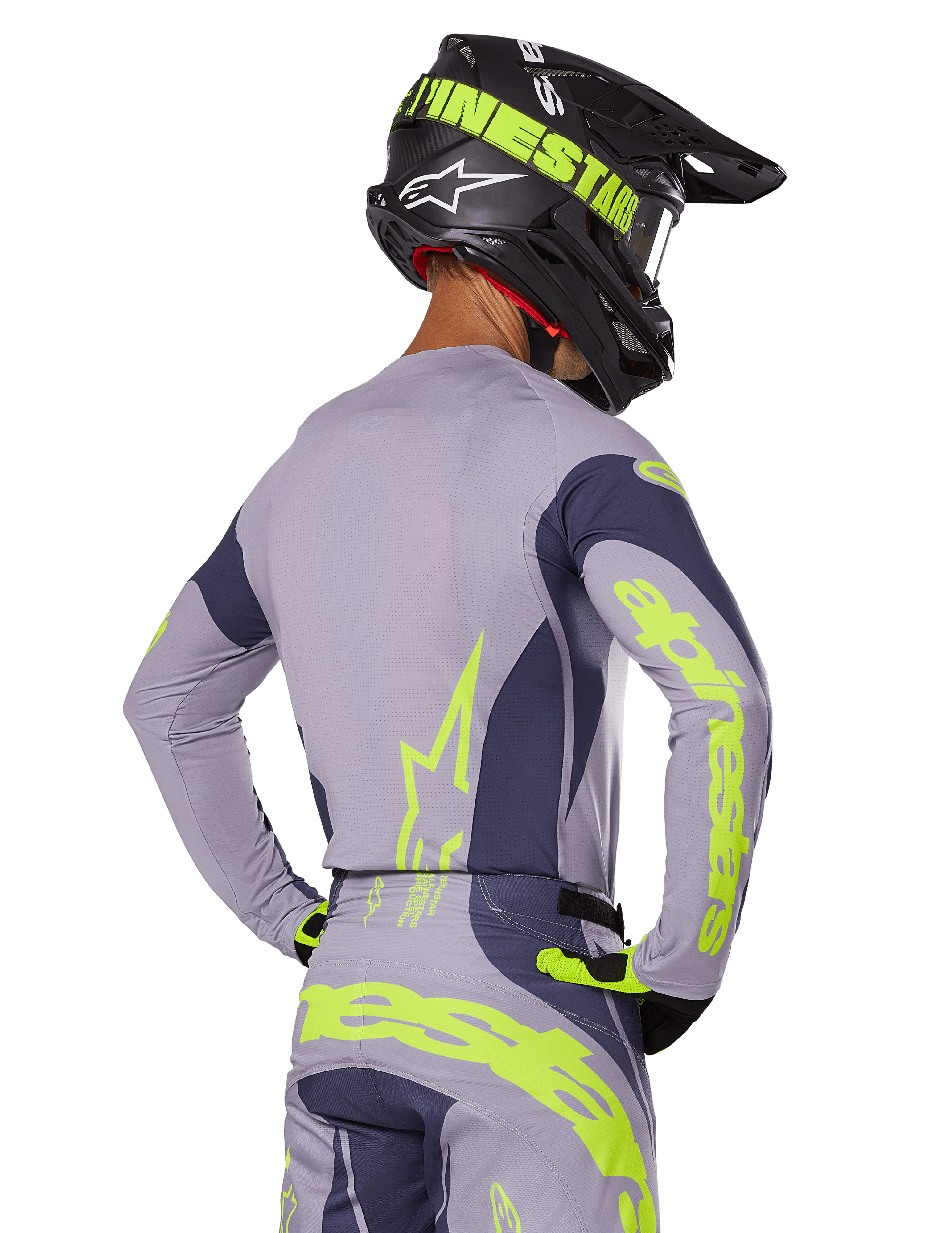 Motocross rider from the rear wearing Alpinestars 2025 Techstar Dreem Gear Set, Gray jersey and pants with vibrant neon yellow-green branding, matching black helmet with neon graphics, professional motocross racing outfit
