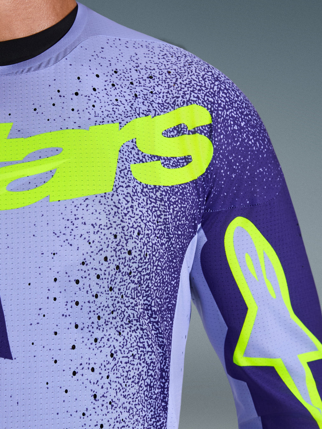 Alpinestars 2026 Supertech Scenz Jersey in Purple Yellow Fluo, close-up shot of the chest and shoulder showing laser-cut perforations, stretch mesh material, and bright yellow fluo branding for pro-level motocross performance.