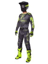 Motocross rider wearing the Alpinestars 2025 Racer Hollow gear set, Dark Camo and Yellow Fluo jersey and pants, black and fluo yellow helmet, matching gloves, and bright fluo yellow boots, coordinated outfit for off-road racing