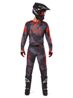 Motocross rider wearing Alpinestars 2025 Racer Hollow Jersey and matching pants in Gray Camo Orange Fluo, complete gear set with black helmet, goggles, gloves, and boots, featuring bold orange logos and camo pattern.