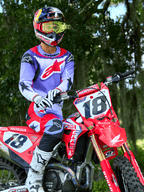 Motocross rider on a red Honda CRF dirt bike, wearing Alpinestars 2025 Fluid Wurx Jersey in Purple and Bright Red, matching purple and red pants, Red Bull helmet with yellow goggles, white Alpinestars boots and gloves, professional MX gear for off-road riding