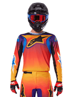Alpinestars 2025 Fluid Wurx Jersey, Multicolor motocross jersey with orange and red gradient and purple accents, worn with matching gear, black helmet with blue and red goggles, and red gloves, featuring a large black star logo on the chest.