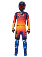 Motocross rider wearing the Alpinestars 2025 Fluid Wurx Gear Set, featuring a vibrant orange, yellow, and blue gradient on the jersey and pants, black Alpinestars logos, paired with blue racing boots, red and black gloves, and a black helmet with red goggles, complete coordinated outfit for off-road racing