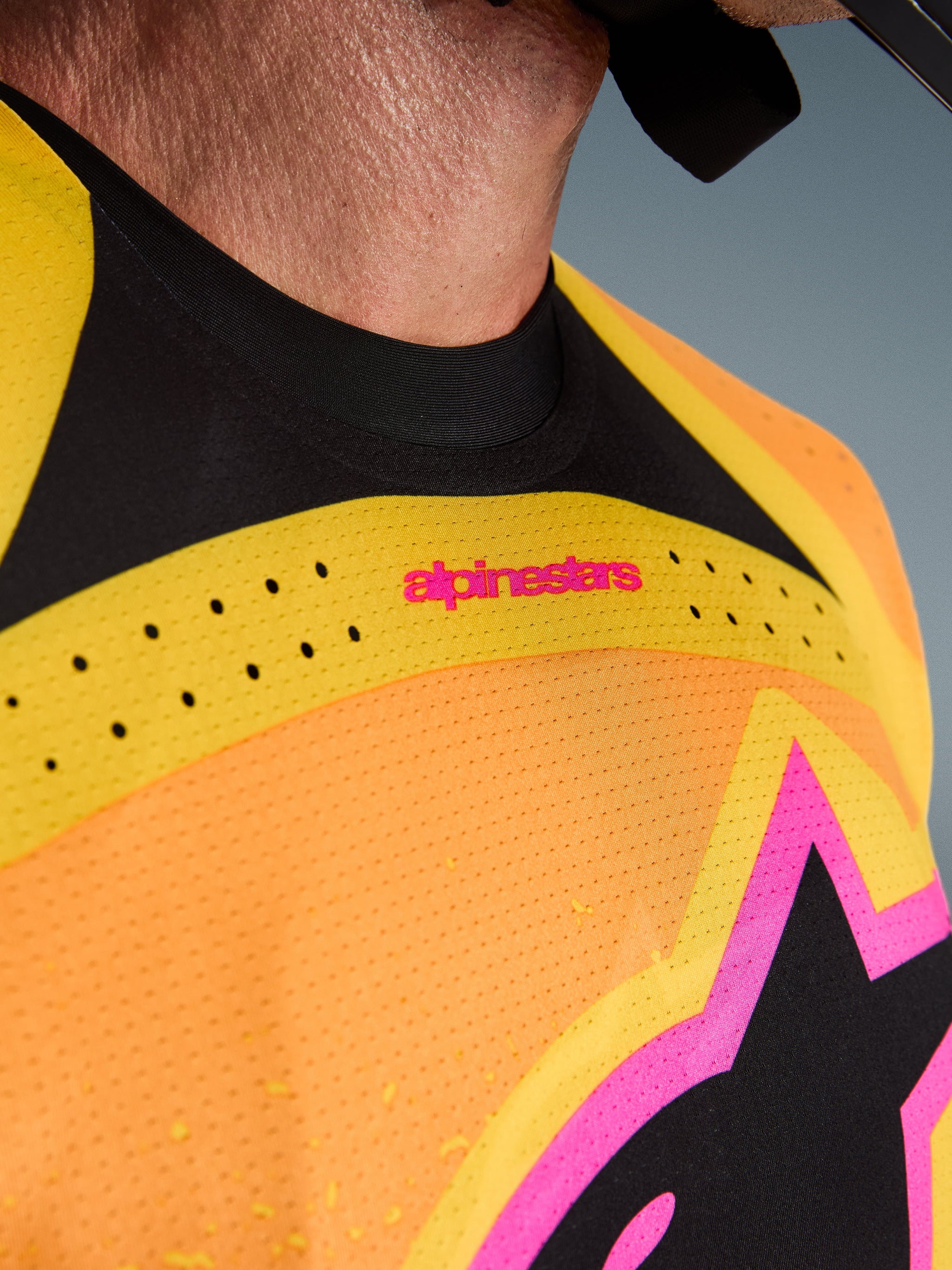 Alpinestars 2026 Techstar Nomur Jersey, Motocross Jersey, Orange Yellow Pink, close-up detail of the chest and collar, featuring laser-cut ventilation, pink branding, and breathable mesh fabric