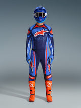 Motocross rider wearing the Alpinestars 2026 Techstar Nomur Jersey in Dark Navy, Orange, and UCLA Blue, paired with matching motocross pants, a blue helmet with goggles, and bright orange racing boots, full coordinated off-road competition gear