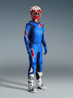 Motocross rider wearing the Alpinestars 2026 Fluid Grid Jersey in Blue Red, paired with matching motocross pants, white and black boots, and a red and white helmet, professional gear set for off-road performance.
