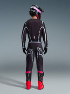 Motocross rider seen from behind wearing the Alpinestars 2026 Fluid Apex Gear Set, black jersey and pants with grey geometric lines and star logos, black helmet with pink accents, bright red and black boots, coordinated motocross racing gear