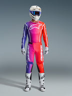 Motocross rider wearing a complete Alpinestars 2026 Fluid Apex racing gear set, featuring a purple, pink, and orange gradient jersey and pants. The coordinated outfit includes a white Alpinestars logo on the chest, a white helmet with blue goggles, and white boots, designed for off-road performance.