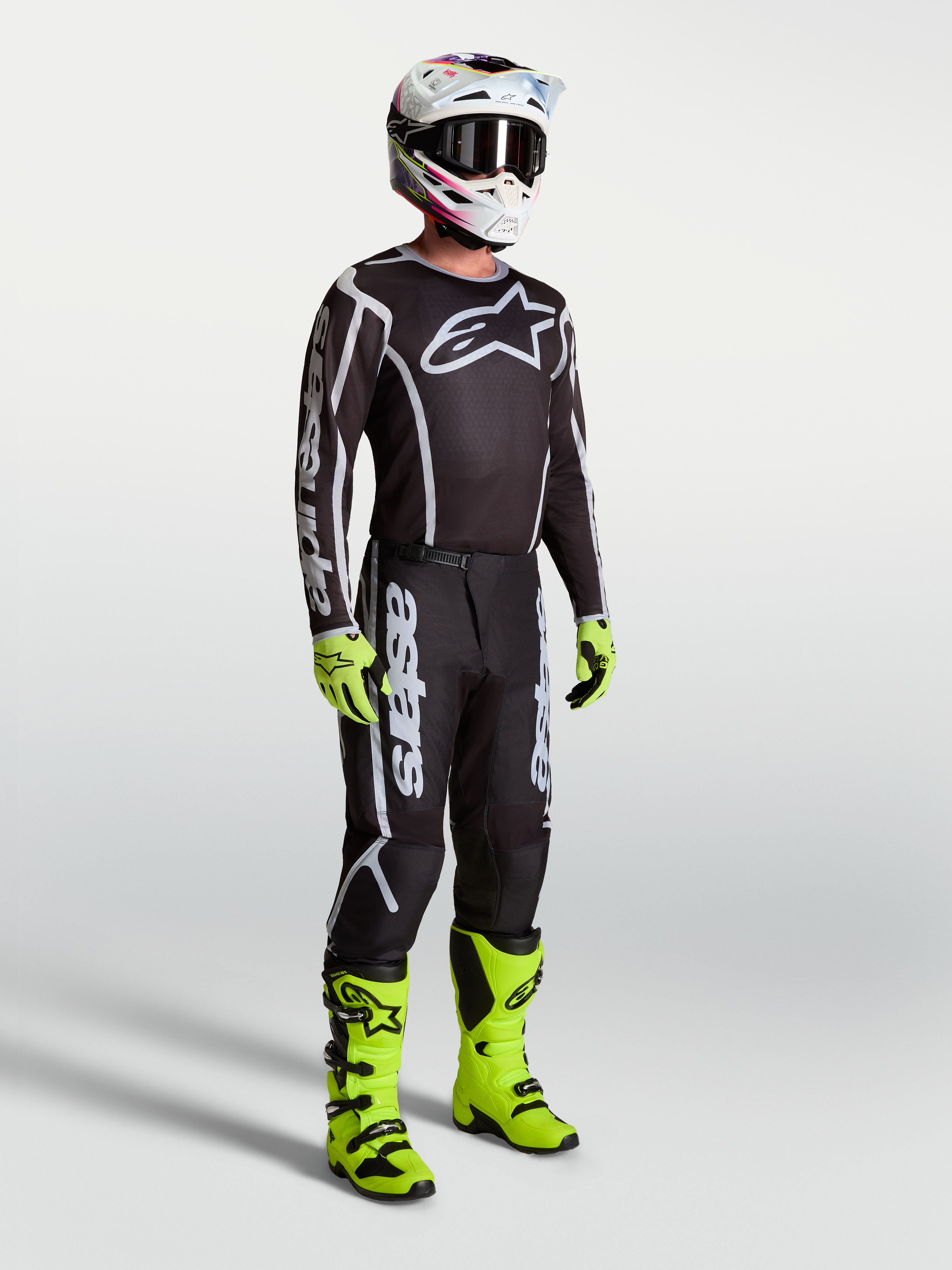 Alpinestars Fluid Apex V2 Jersey, Black and Silver motocross apparel on model with neon green boots and gloves.