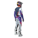Motocross rider seen from behind wearing the Alpinestars 2024 Racer Hoen Jersey in Light Gray Hot Orange Black, navy back panel with orange star logo, purple sleeves, worn with matching racing pants and white boots.