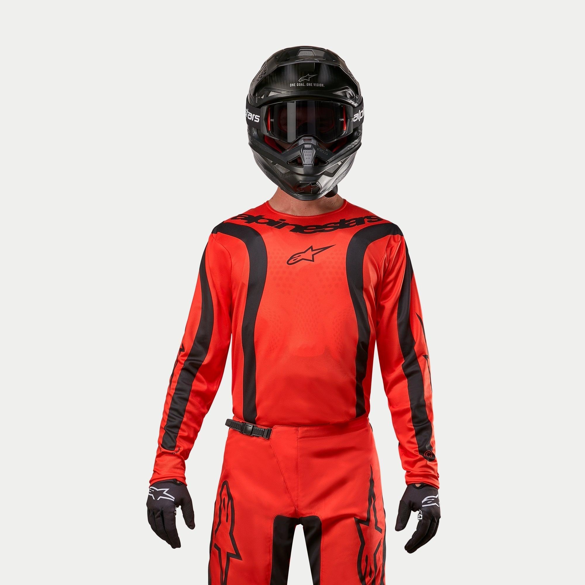 Motocross rider wearing Alpinestars 2024 Fluid Lurv Jersey, Hot Orange and Black, matching motocross pants, black helmet with goggles, and black gloves, coordinated gear for off-road racing