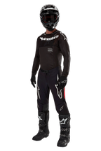 Motocross rider wearing complete racing gear, 2024 Supertech Ward Jersey in Black Red Berry, black jersey with white Alpinestars branding, black pants with red side panels and large white Astars logos, black helmet, gloves, and boots, coordinated pro-level outfit for off-road racing