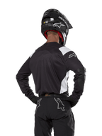 Alpinestars Techdura Jersey, Black with white shoulder accents, back view of motocross rider wearing matching black pants and helmet, reinforced elbow patches, enduro and off-road racing gear