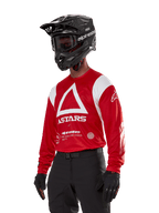 Alpinestars Techdura Jersey, Motocross Jersey, Bright Red and White, featuring a bold white triangle design and ASTARS branding, worn with a black helmet and gloves, durable and moisture-wicking off-road racing gear