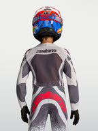 Alpinestars Youth Supertech Swan Motocross Jersey and Pants in gray and white with red fluo accents, back view on-model.