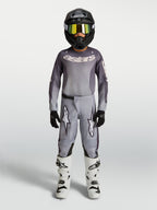 Alpinestars 2027 Youth Fluid Amber Jersey and Gear Set, gray and sand motocross outfit with black helmet and white boots.