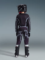 Youth motocross rider seen from behind wearing the 2026 Youth Fluid Apex Jersey in Black and Gray, matching motocross pants with large white logo graphics, black helmet, and black and white Tech Series boots, complete performance gear set for off-road riding.