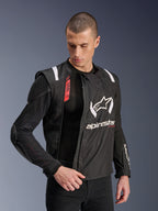 Alpinestars T-Stunt Air Jacket, Black and White motorcycle jacket, worn by male model, showcasing modular mesh construction and exposed internal armor on shoulder and elbow, Alpinestars branding on chest, Tech-Air Ready feature, sports-cut for road riding