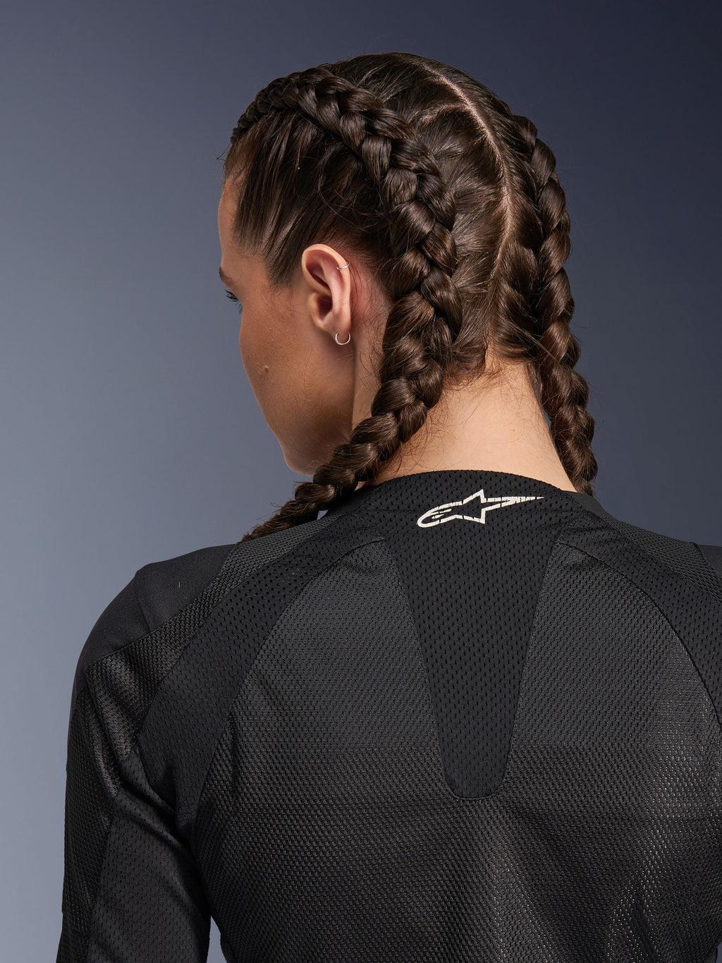 Alpinestars Woman Stella Troop-Air Jacket, Black, detailed rear view of upper back and neck, woman with French braided hair, featuring a white Astars logo on the collar and lightweight 2D tech mesh fabric for ventilation