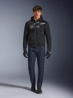 Motorcycle rider wearing the Alpinestars Chrome Superairflow Hoodie in Black and Gray, paired with dark blue jeans, black motorcycle gloves, and black shoes. The hoodie features a large stylized logo on the chest and a 3D mesh texture for high-temperature performance.