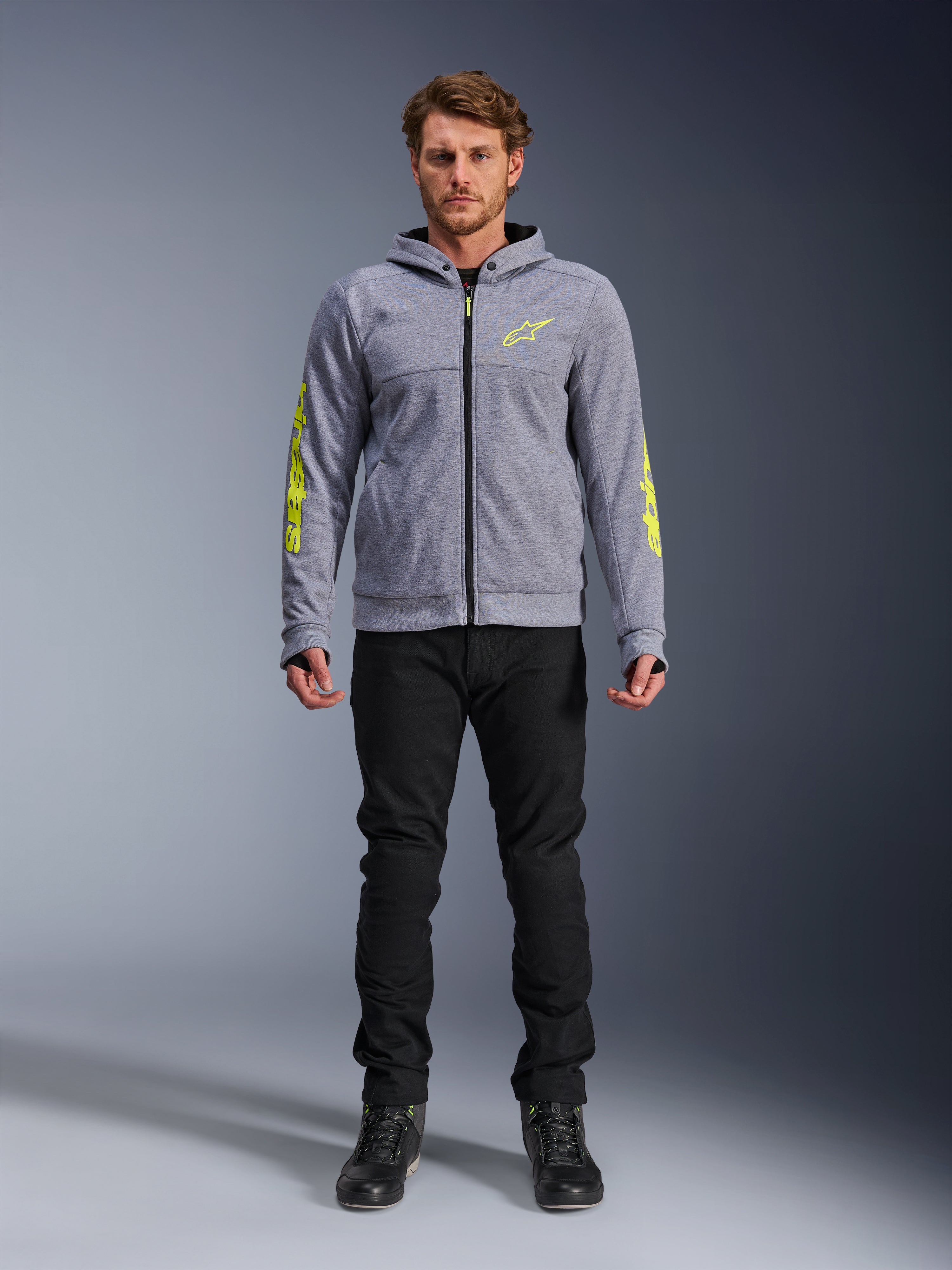 Alpinestars Chrome V2 Sport Hoodie, Gray Heather with Fluorescent Yellow accents, urban motorcycle apparel, featured with black pants and black riding shoes, technical fleece with bold yellow branding on sleeves and chest, casual street style for riding