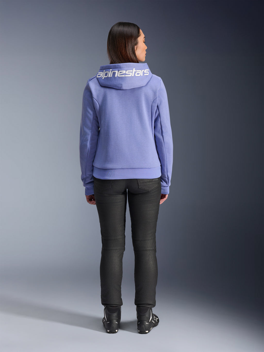 Alpinestars Stella Chrome V2 Sport Hoodie, Blue Violet, back view of a woman wearing the hoodie featuring white Alpinestars logo across the hood, paired with black pants and riding boots, casual urban motorcycle apparel