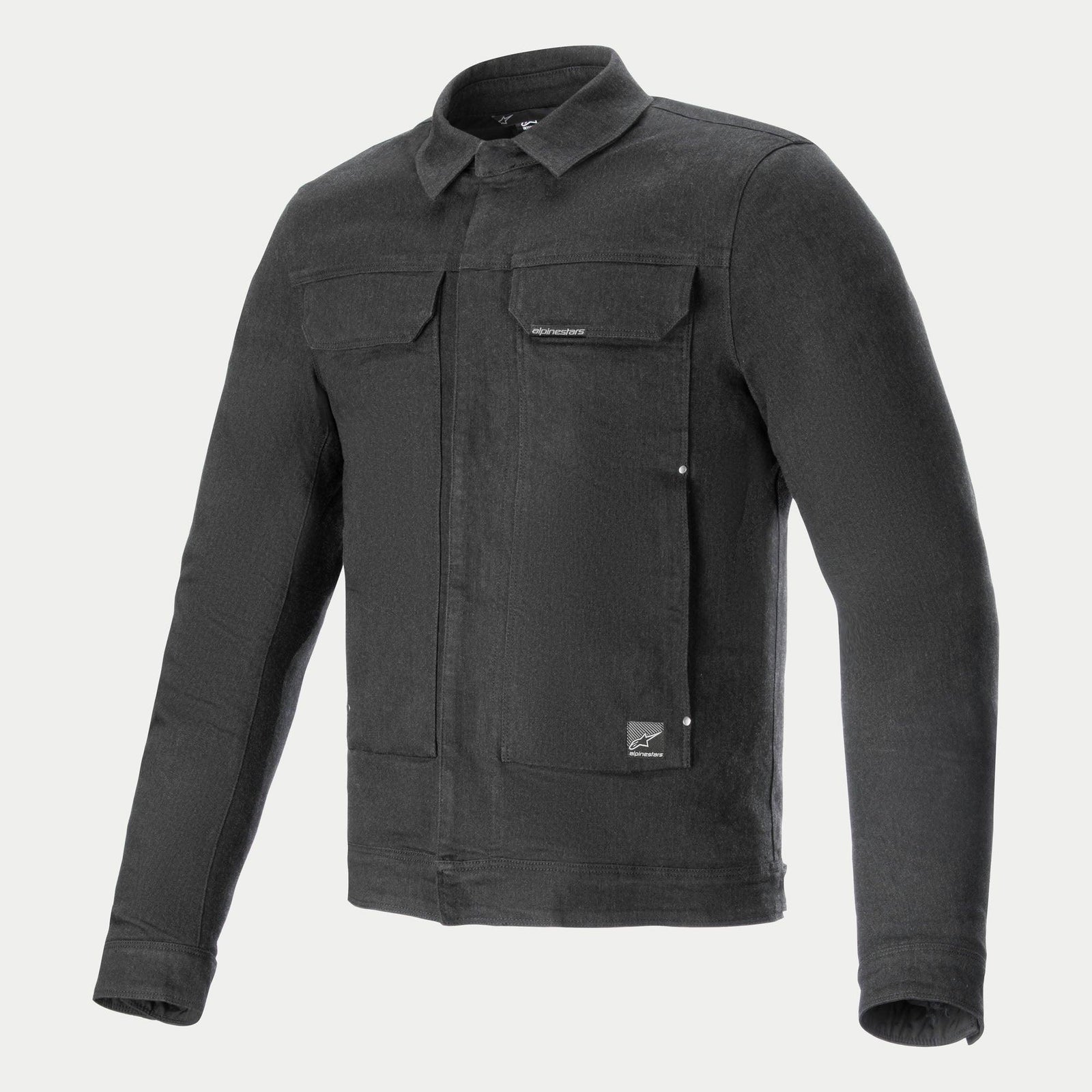 The Garage Jacket by Alpinestars EU is a long-sleeved, dark gray, urban-styled jacket with a collared neckline and four front pockets. Made from stretch cotton denim, it features a metallic zipper concealed under a flap and button closures on the pockets and wrists. A small tag is visible on the lower pocket.