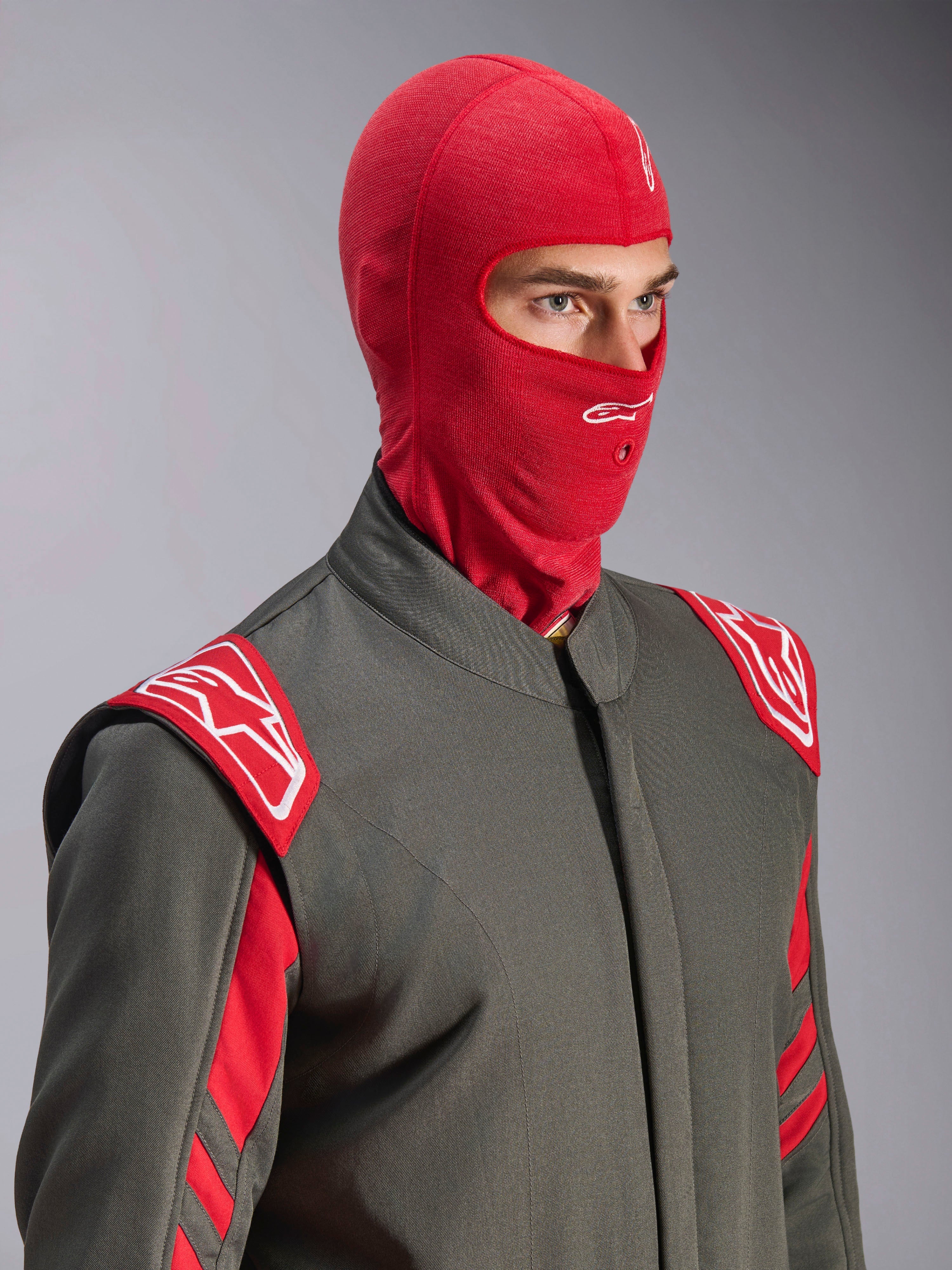 Alpinestars ZX Evo V3 Balaclava, Red, worn by a driver in a gray racing suit with red and white accents, featuring a white Astars logo on the forehead and a hydration tube port, flame-resistant base layer for auto racing