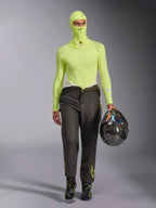 Alpinestars ZX Evo V3 Balaclava in Yellow Fluo, worn with matching long-sleeve base layer top and dark grey racing pants, male model holding a carbon fiber helmet, professional auto racing gear