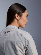 Woman wearing the Alpinestars Stella C-1 Air Jacket in Silver, close-up side-back view showing the black Alpinestars logo, tech mesh ventilation panels, and a clean contemporary urban motorcycle design.