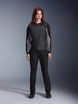 Alpinestars Women Stella Tech-Air® 3 V2 System, Black Motorcycle Airbag Vest, worn over a black and grey long-sleeved technical layer with matching black riding pants, featuring a diagonal zipper and LED status display, tailored female fit for road and touring riders.