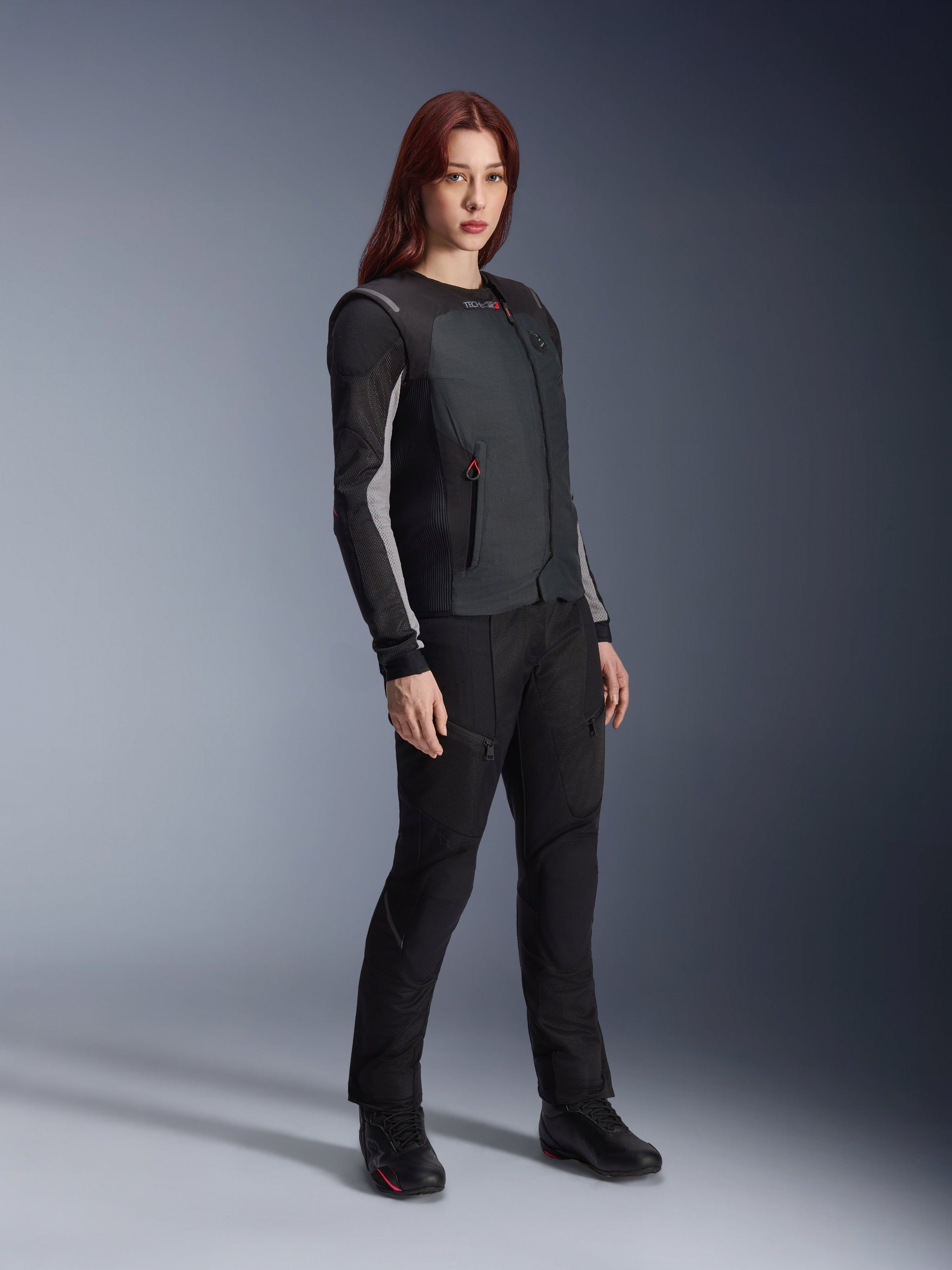 Alpinestars Stella Tech-Air 3 V2 System, Women's autonomous motorcycle airbag vest in Black, worn with matching black textile riding pants and boots, featuring a slim tailored fit for urban and touring protection.
