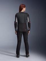 Rear view of a woman wearing the Alpinestars Stella Tech-Air® 3 V2 System in Black, an autonomous motorcycle airbag vest, styled with black riding pants and a base layer featuring pink logos, showing the sleek and tapered female fit for urban and road riding.
