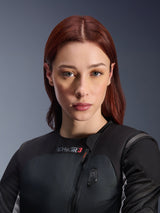 Woman wearing the Alpinestars Stella Tech-Air 3 V2 System, Black autonomous motorcycle airbag vest, close-up portrait featuring the diagonal zipper and integrated LED status display, tailored for women