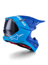 Alpinestars Supertech M10 Flood Helmet, Motocross Helmet, Bright Blue and Navy Blue with exposed Black Carbon fiber, rear-side profile showing ventilation ports and white logo, red interior lining, advanced aerodynamic design for off-road performance