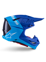 Alpinestars Supertech M10 Flood Helmet, Motocross Helmet, Metallic and Medium Blue with Black Carbon accents, side profile view, featuring a white logo, aerodynamic design with ventilation ports, carbon fiber texture details, professional off-road racing protection