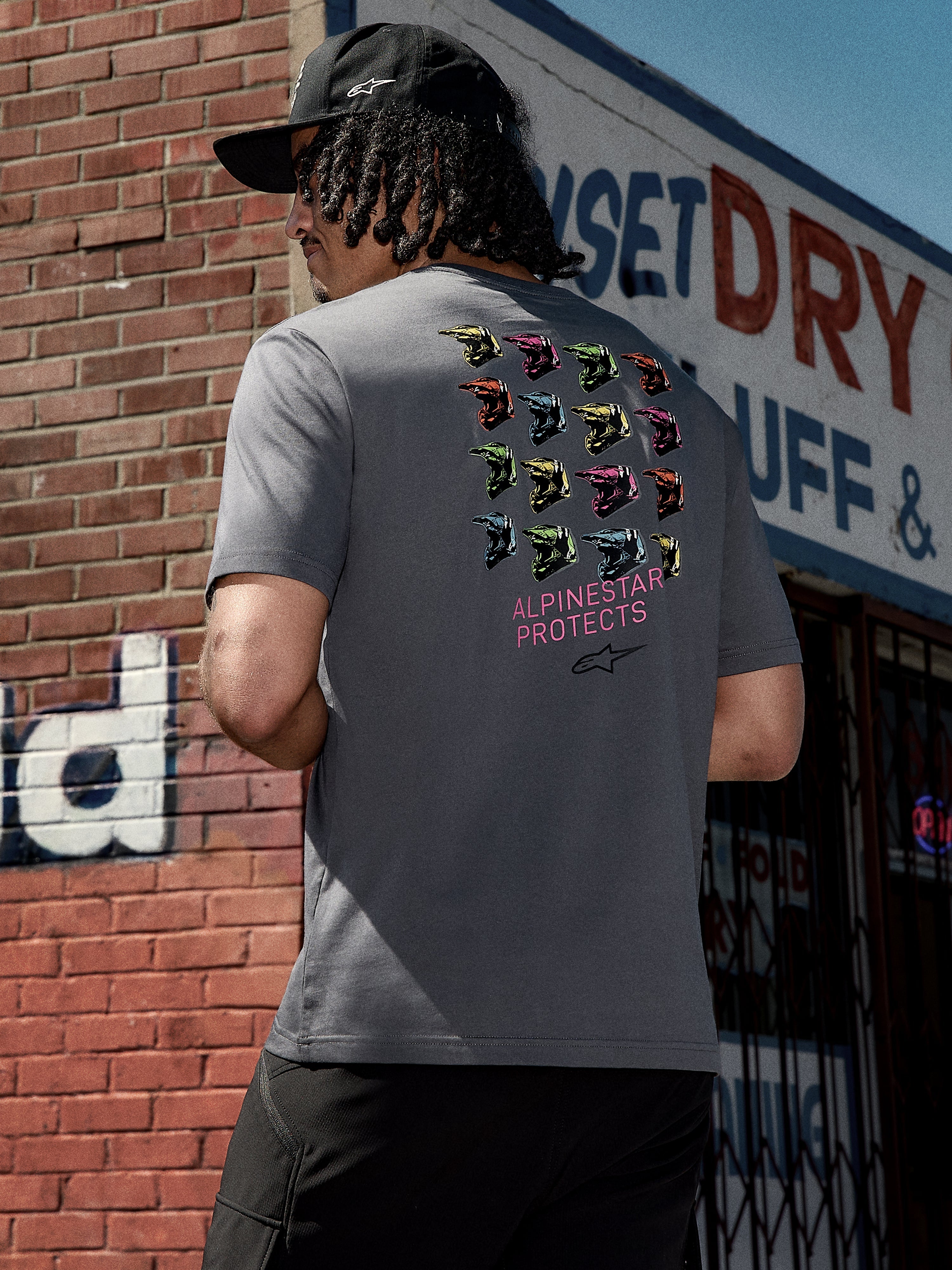 Alpinestars Pop Helmet CSF Tee, Short Sleeve T-Shirt, Charcoal Gray, back graphic featuring colorful M10 helmets and pink "ALPINESTAR PROTECTS" text, casual motorsport-inspired streetwear