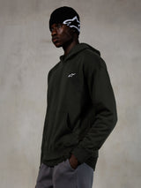 Alpinestars Essentials Ageless Hoodie, Off Black, Male model wearing casual streetwear, dark charcoal stone-washed fleece with a small white star logo, paired with a black Alpinestars beanie and grey pants