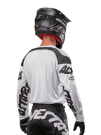 Alpinestars 2024 Racer Hana Jersey, White and Black, back view showing ergonomic fit and bold sleeve branding, paired with a black motocross helmet and matching black and white pants, high-performance racing gear for off-road riding