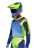 Alpinestars 2024 Racer Hoen Jersey, Motocross Jersey, Yellow Fluo and Blue Night Navy with red logos, worn with a matching yellow, blue, and red helmet and blue gloves, vibrant gear for off-road racing
