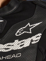 Close-up of the Alpinestars Stella GP-R7 2-Piece Leather Suit in Black, featuring perforated leather panels, a large white Alpinestars logo on the chest, and breathable stretch fabric sections.