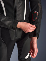 Close-up of the Alpinestars Stella GP-R7 2-Piece Leather Suit in Black, focusing on the forearm zipper adjustment, featuring perforated leather construction, white accents, and the Tech-Air compatible branding on the sleeve.