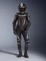 Woman rider wearing the Alpinestars Stella GP-R7 2-Piece Leather Suit in black with white accents, complete with a full-face carbon fiber helmet, black racing gloves, and boots, featuring perforated leather panels and integrated protective armor, professional motorcycle racing gear for track and street performance