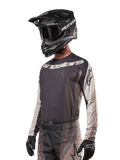 Alpinestars 2024 Techstar Pneuma Jersey, Motocross Racing Jersey, Dark Sand and Iron Dust Gray, long-sleeved performance top with laser-cut perforations and white branding, worn with matching pants and black helmet, athletic fit for off-road riding.