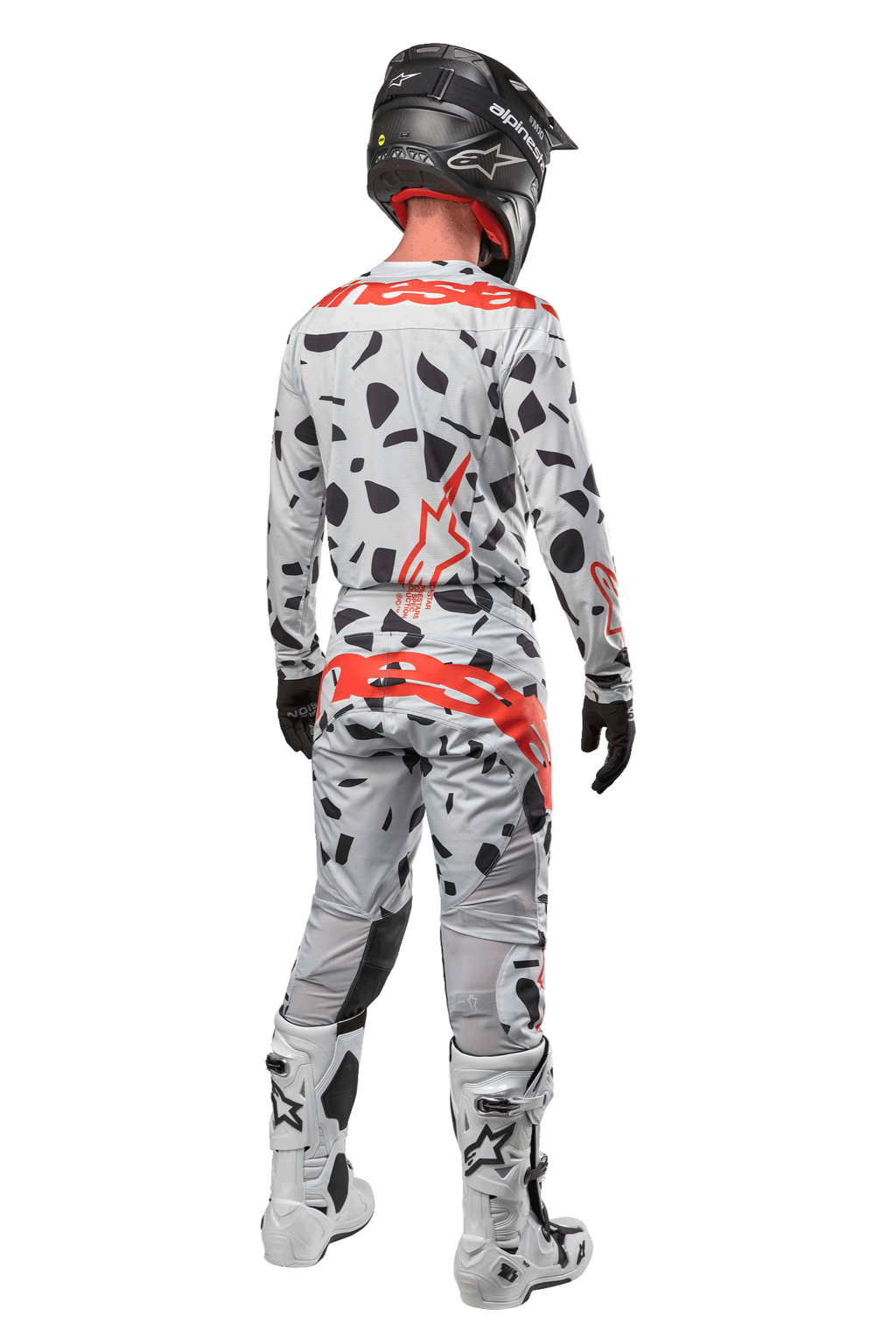 Motocross rider from the back wearing Alpinestars 2024 Techstar Rantera Pants, Haze Gray Camo with black spots and red logos, matching jersey, black helmet, and white boots, complete off-road racing outfit